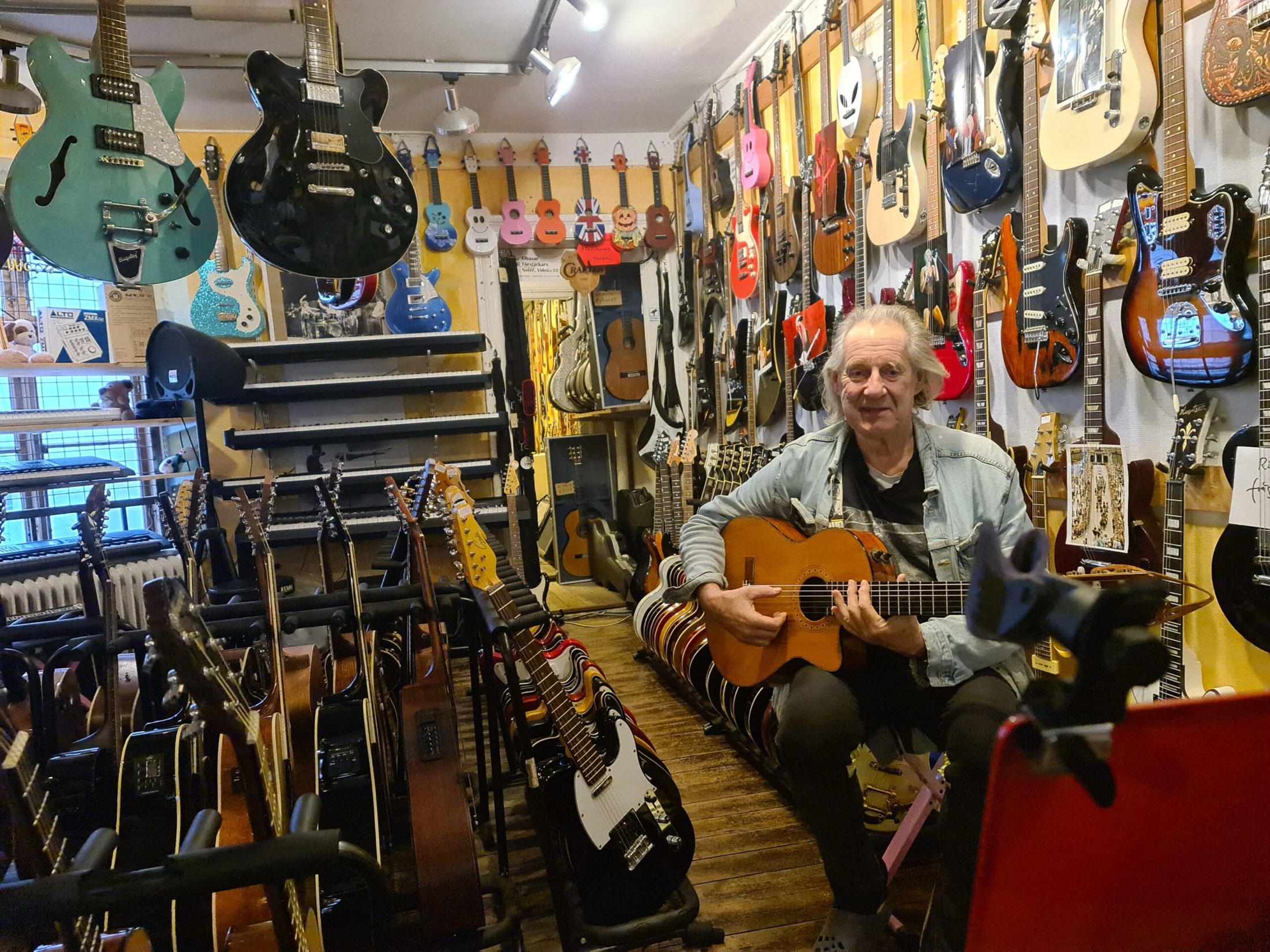 Roffe spelar gitarr i butiken på Bruksgatan, omgiven av gitarrer